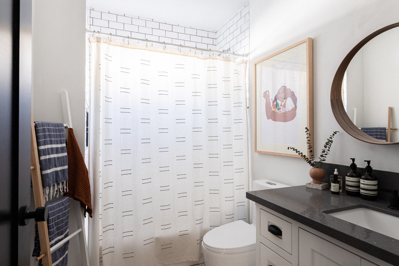 bathroom with shower, toilet, vanity cabinets and circular mirror