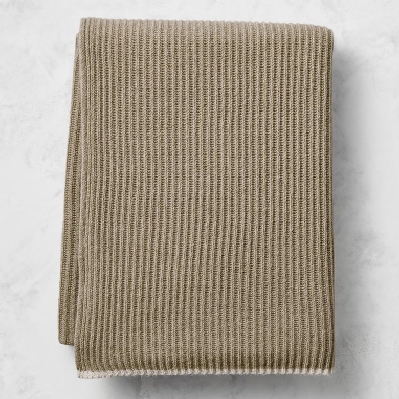 A camel-colored knit cashmere blanket on a marble surface.