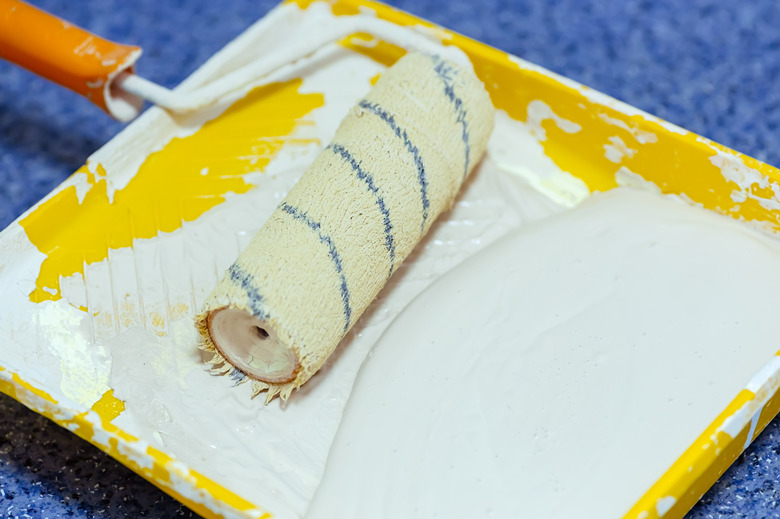 Paint roller in a yellow tray with white paint