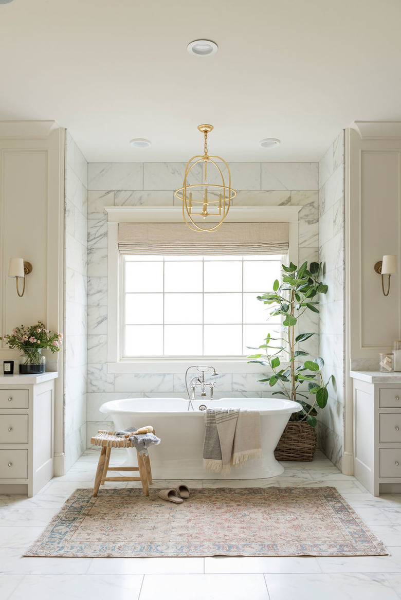 traditional bathroom idea with marble tile, creamy cabinets