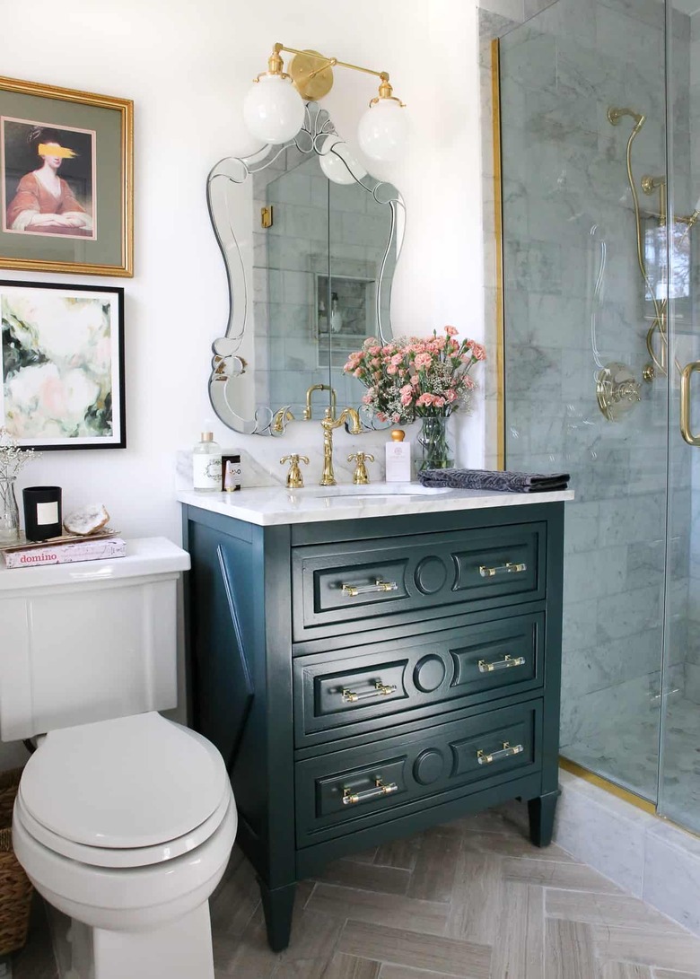 Blue traditional bathroom vanity idea with elegant mirror and vase of fresh flowers