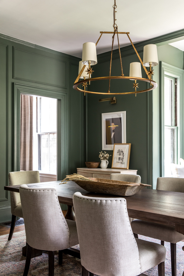 green traditional dining room with wooden table and brass chandelier