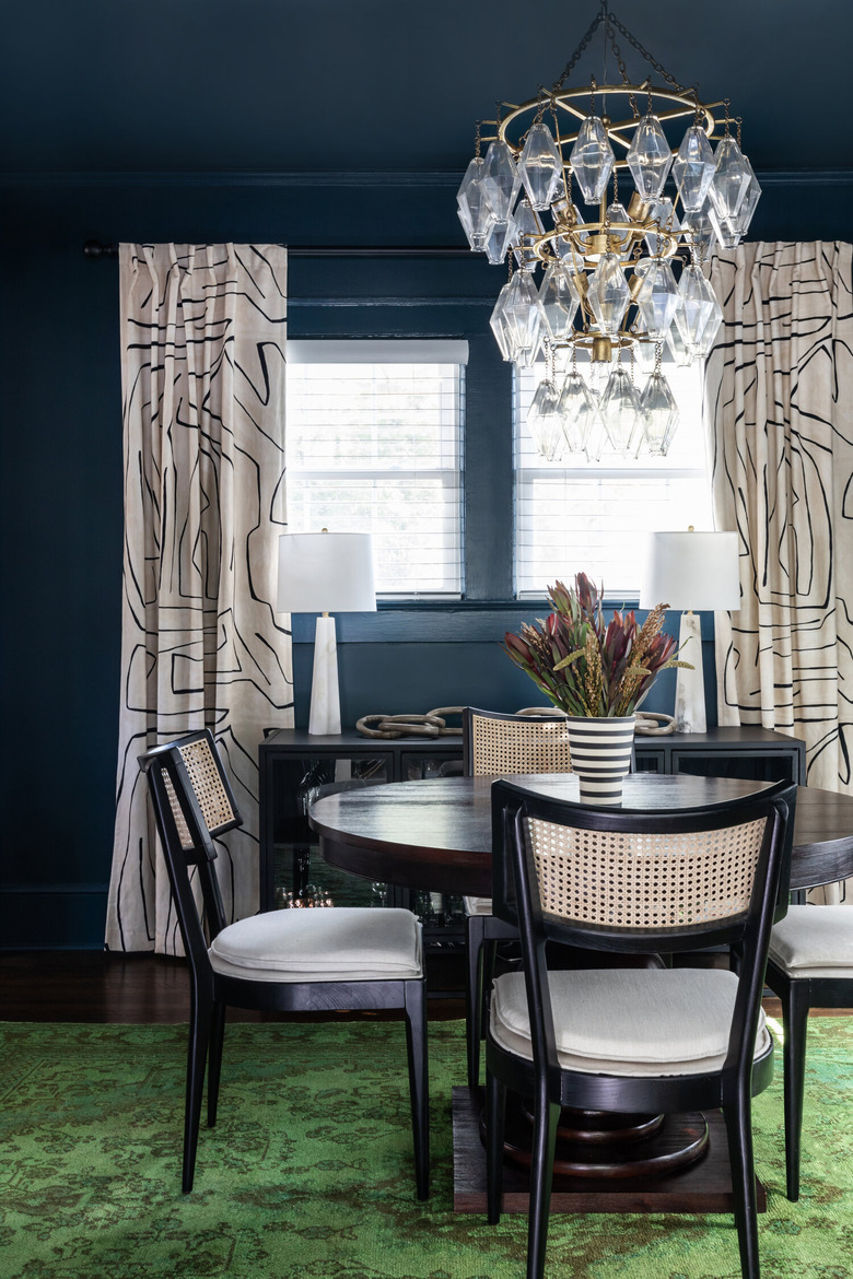 blue traditional dining room with green rug and chandelier