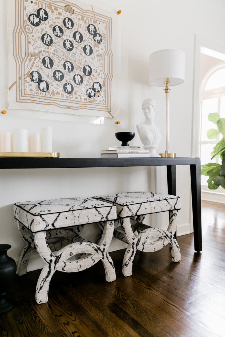 Traditional entryway table with upholstered stools and black and white decor