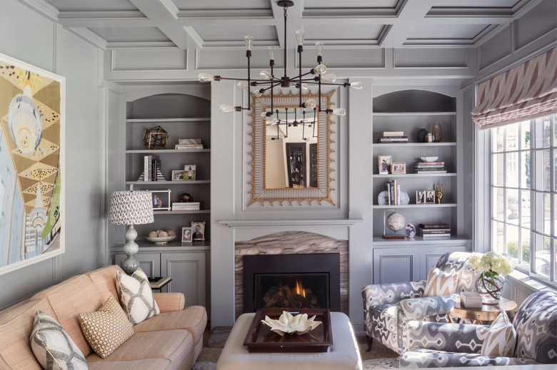 gray living room with traditional fireplace and ornate mirror and chandelier