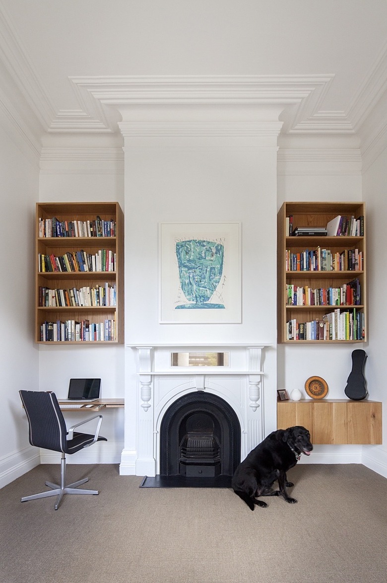 white home office with traditional fireplace and shelving on both sides