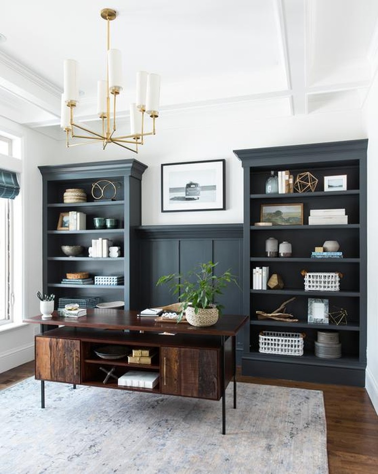 traditional home office with blue green built-ins and a brass chandelier