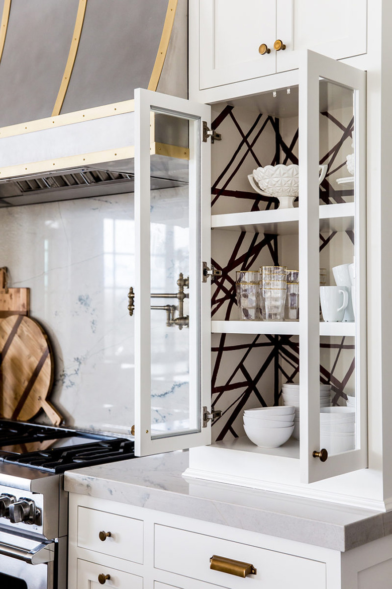 Traditional kitchen design with white cabinets and black and white wallpaper inside cabinet