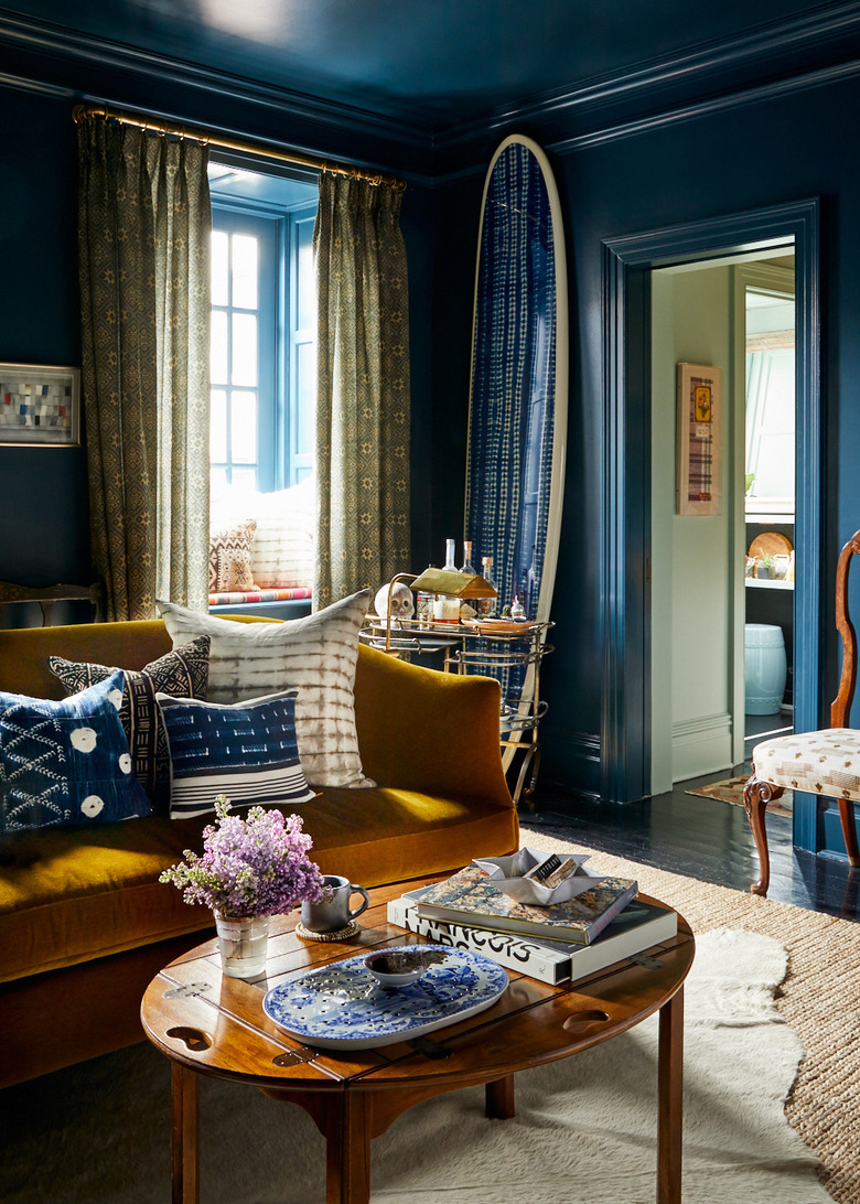 blue traditional living room with mustard velvet sofa and layered rugs