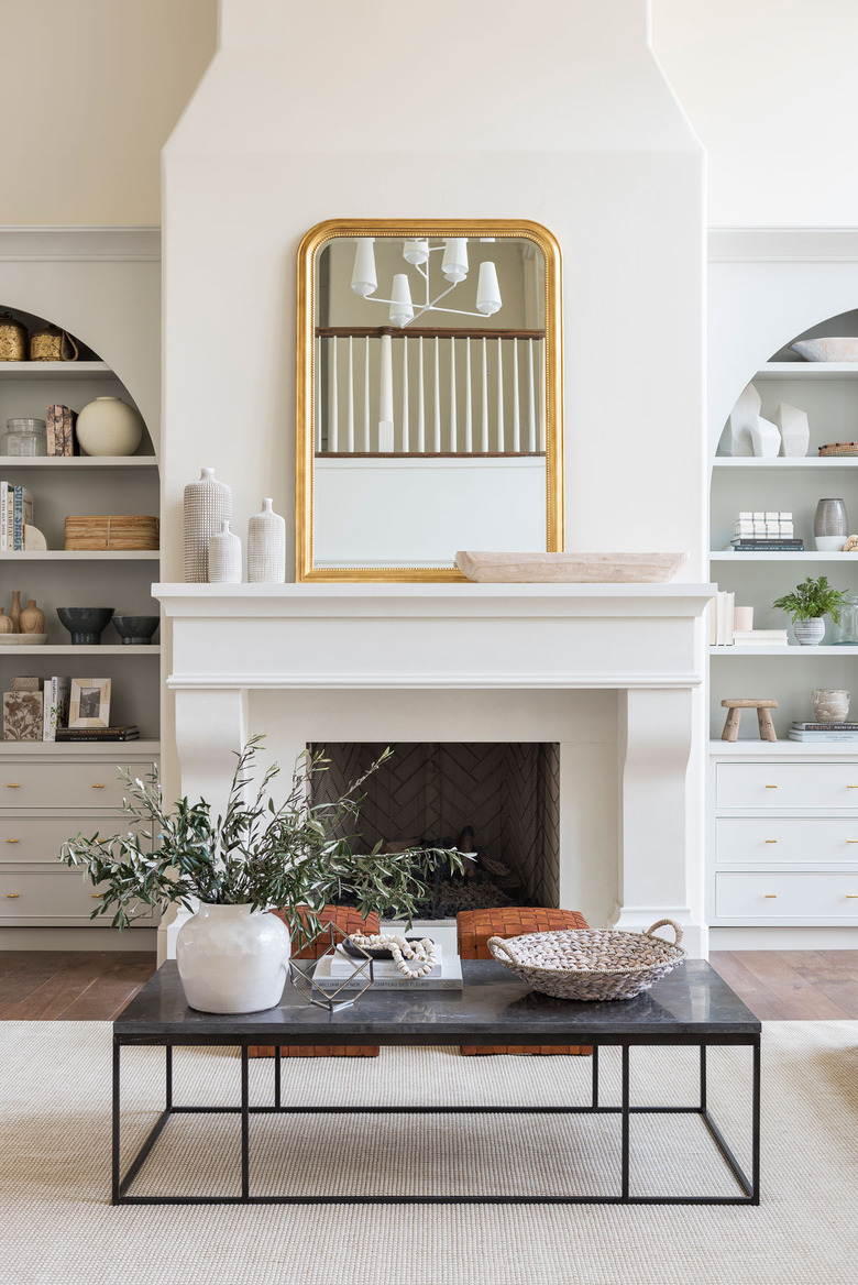 traditional mantel decor with white vases, gold mirror, and wood bowl