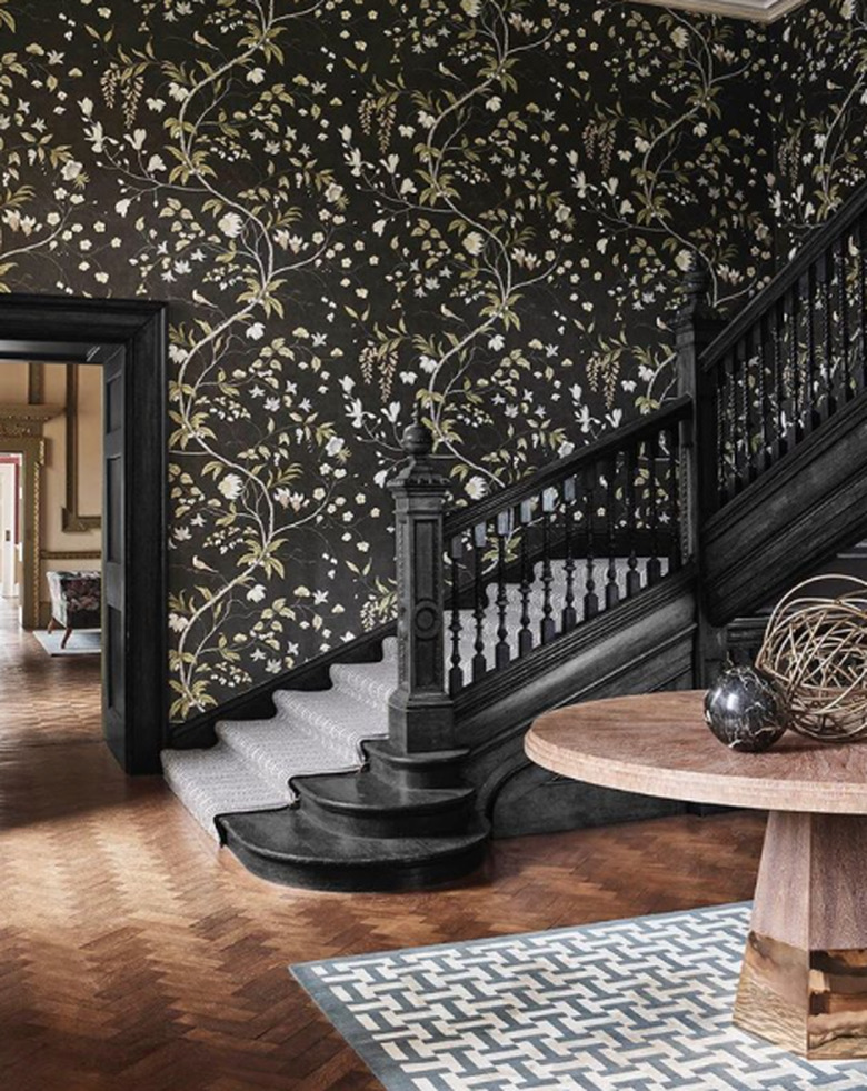 traditional staircase and floral wallpaper and black railing