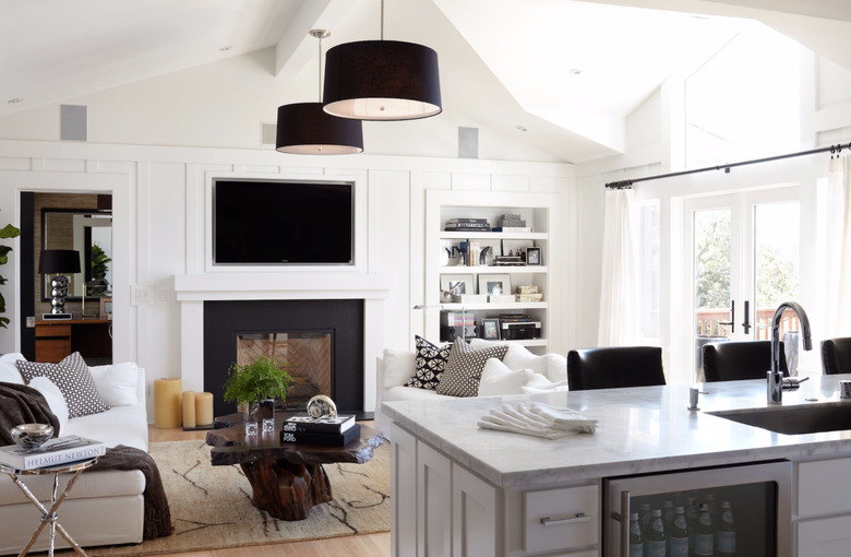 transitional family room with two matching black pendant lamps, white sofas, built in flat screen tv and shelving, fireplace, hard wood floors.