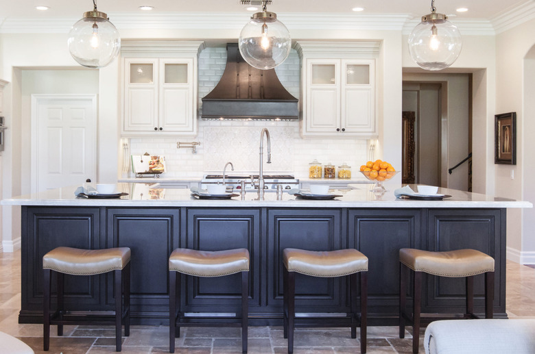 brown travertine kitchen flooring with blue island and white cabinets