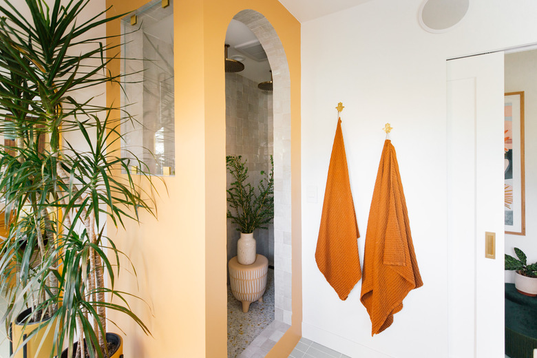 golden yellow bathroom color idea with accent wall and orange towels