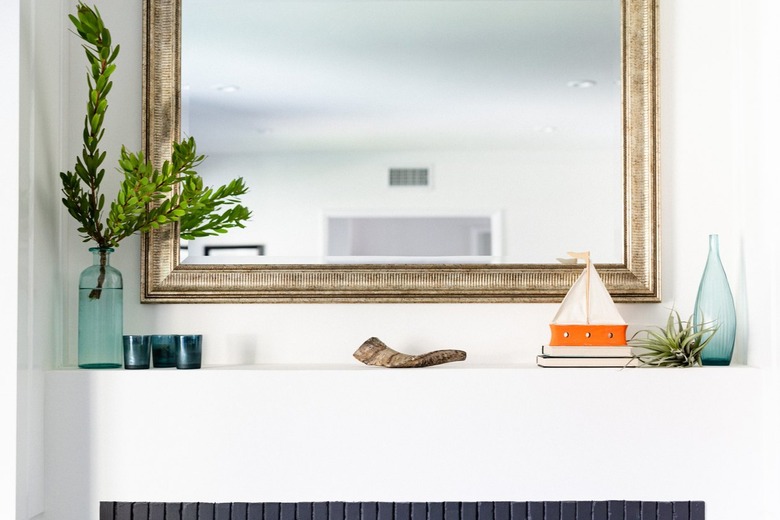 A gold framed mirror over a fireplace.