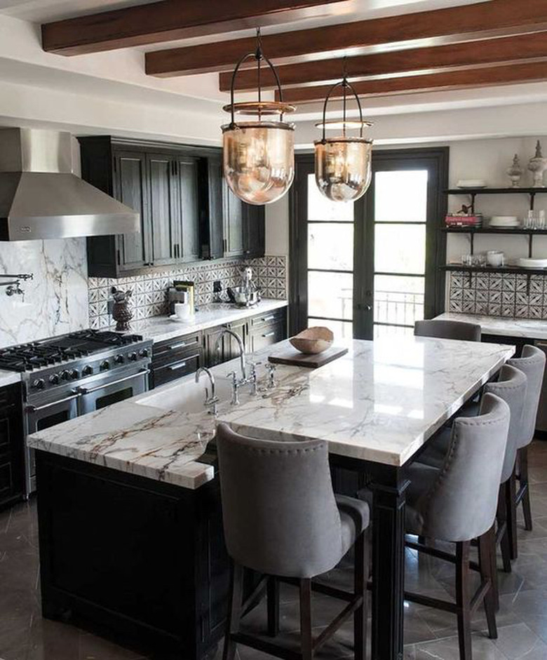 two tier kitchen island with black base and marble countertops and glass pendant lights