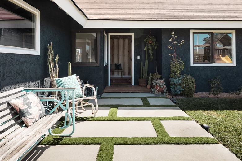 Staggered concrete square patio, of a black-neutral house, with a stucco siding, and eclectic outdoor furniture.