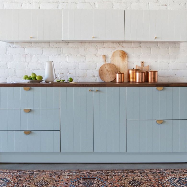 two-tone kitchen color idea with light blue and white cabinetry and patterned rug