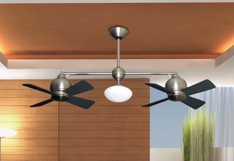 A dual-head fan hanging from an orange ceiling.