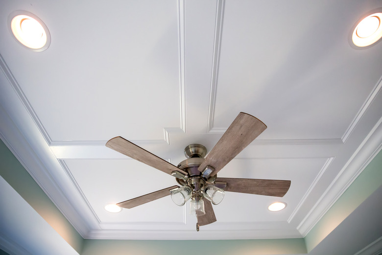 White tray ceiling in small new construction house with windows and a fan