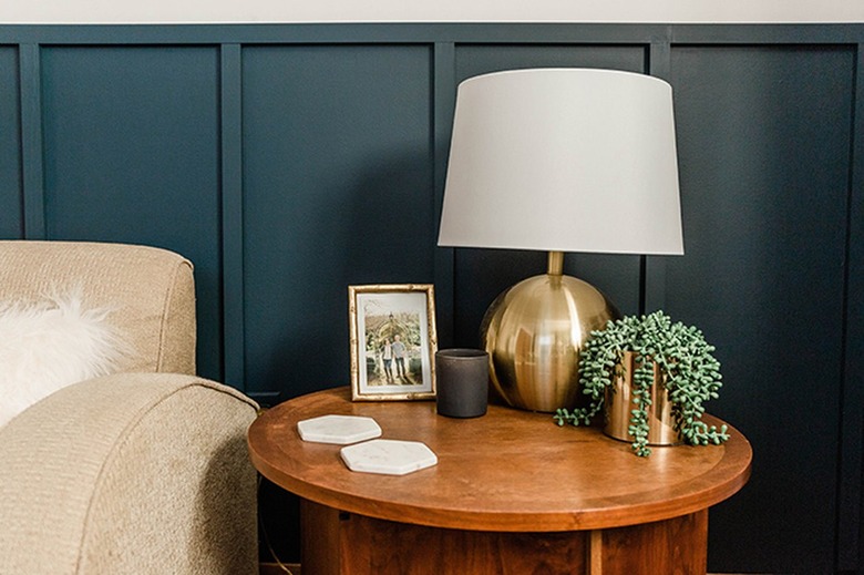 Blue board and batten wall, wood side table with a table lamp, and a beige accent chair