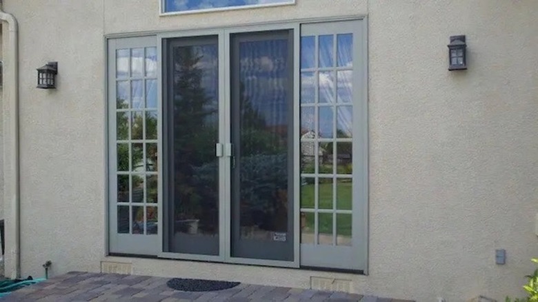 A set of sliding screen doors on a back patio on a stucco house