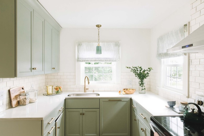 green u-shaped kitchen with white tile backsplash