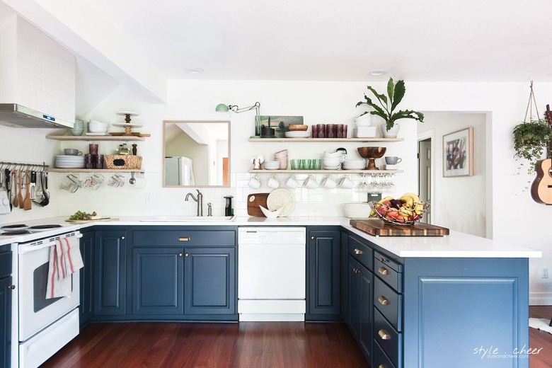 blue and white u-shaped kitchen with floating shelves