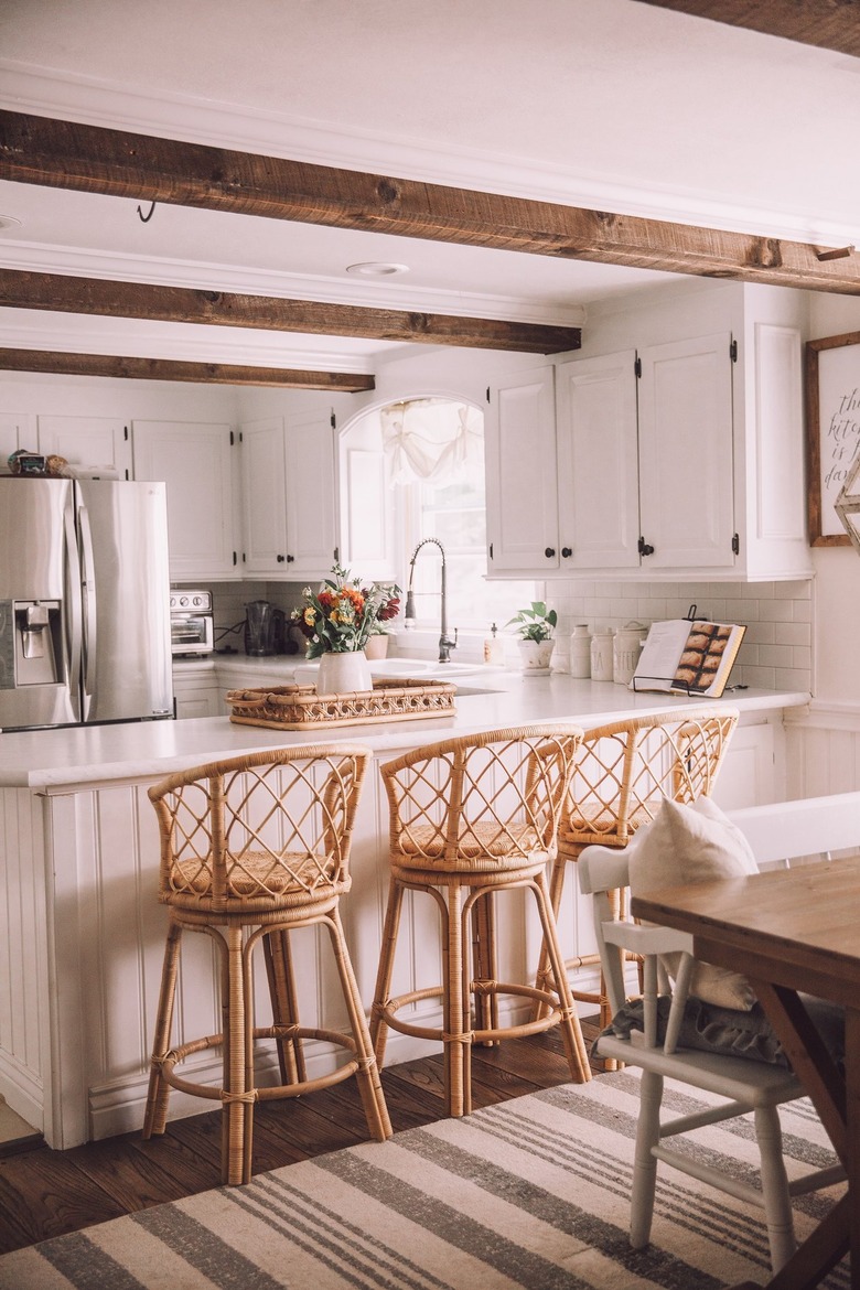 white u-shaped kitchen with rattan bar stools