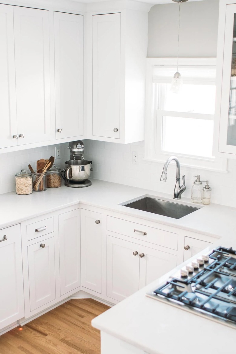 white kitchen with stainless steel sink and window