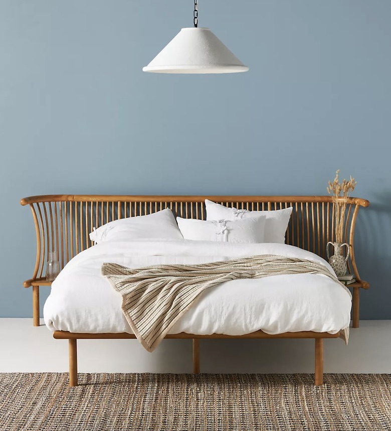 wood bed frame with white sheets and white lamp hanging above