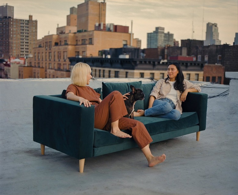 two people sitting on green couch with city landscape in the background