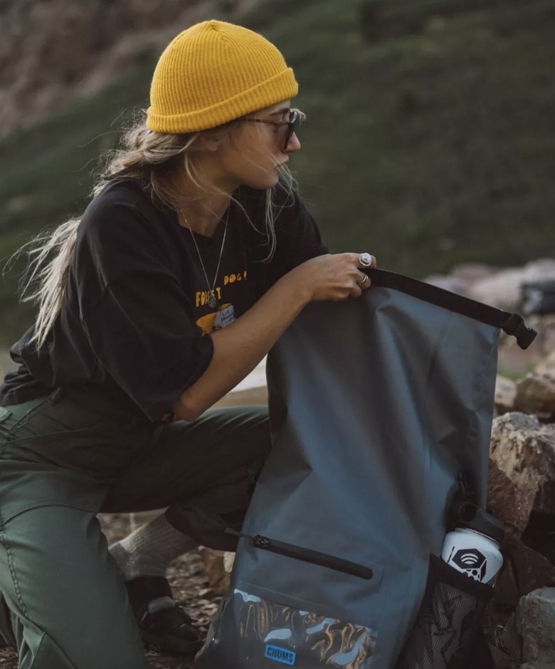 Image of hiker reaching for somthing in a Chums Downriver Rolltop Backpack