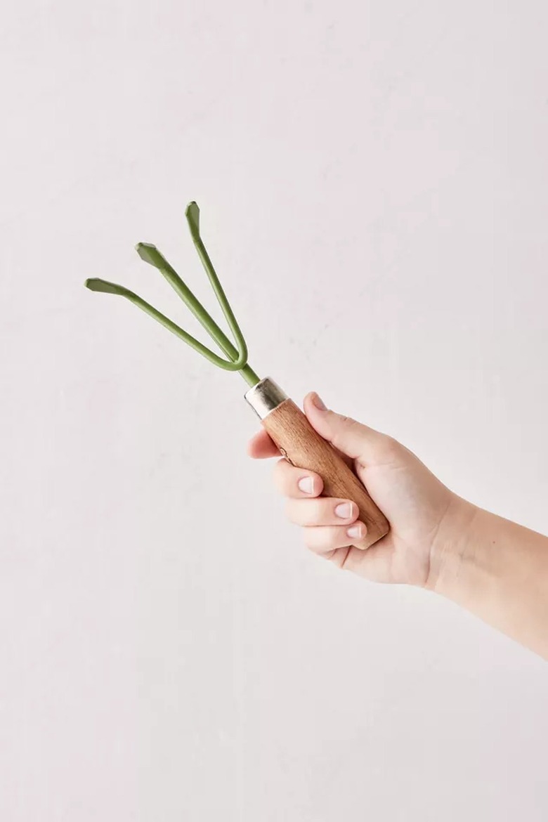 hand holding a green hand rake