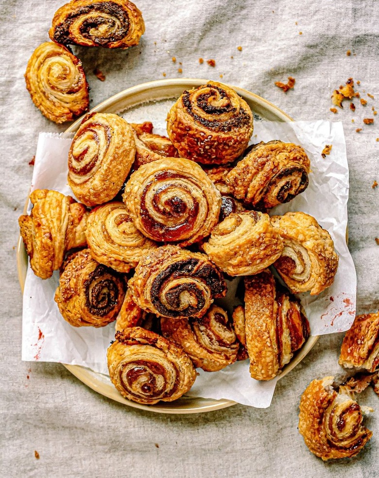 Vegan chocolate and jam rugelach piled on a plate on a white cloth.