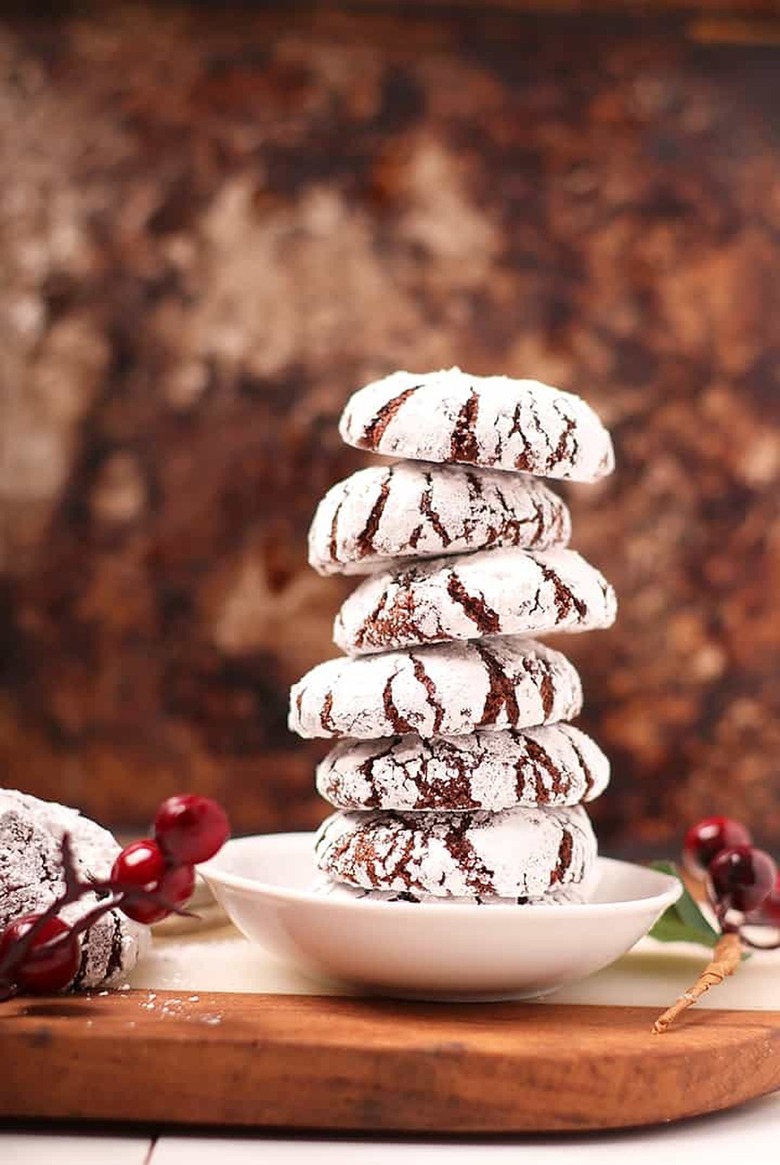 Chocolate cookies with powdered sugar topping stacked on a plate