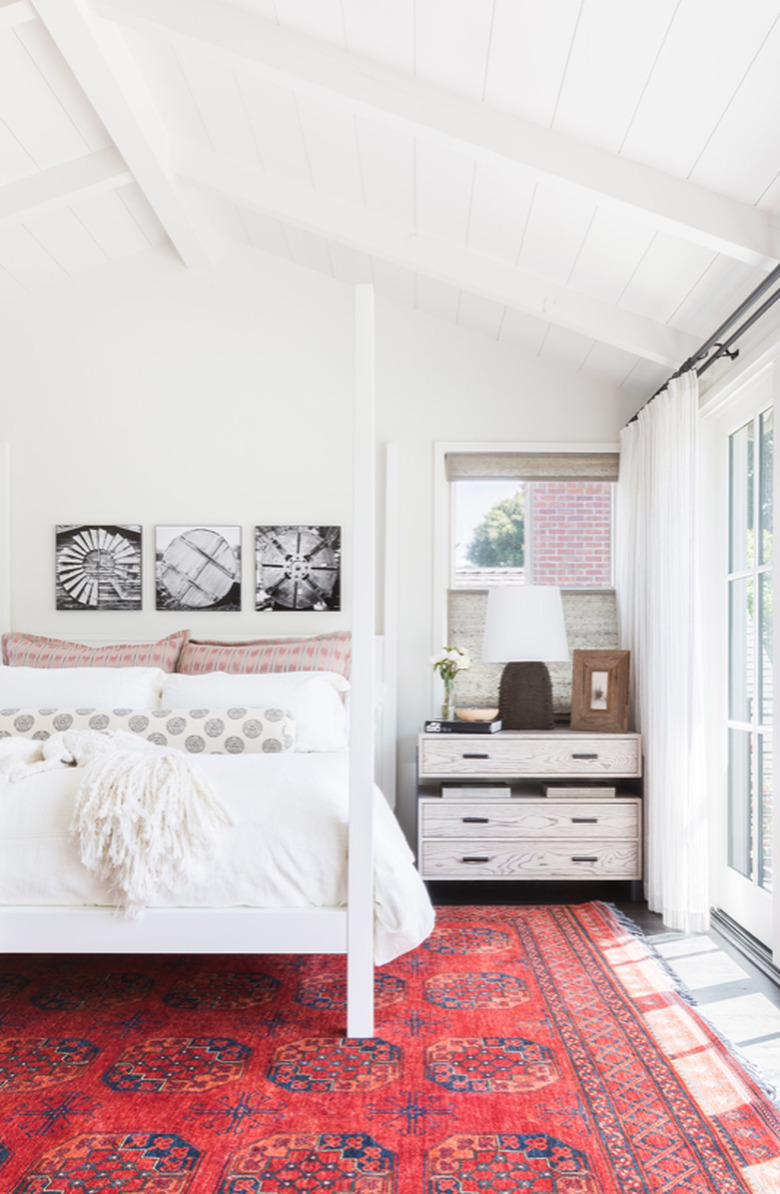 White arch ceiling bedroom and white bedding with vermillion color area rug.