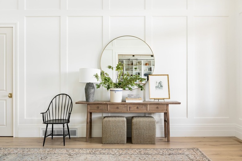 A bright entryway table decorated with a lamp plant, and artwork.