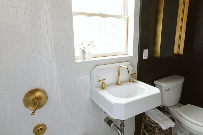 sink with a gold faucet and black wall in a bathroom