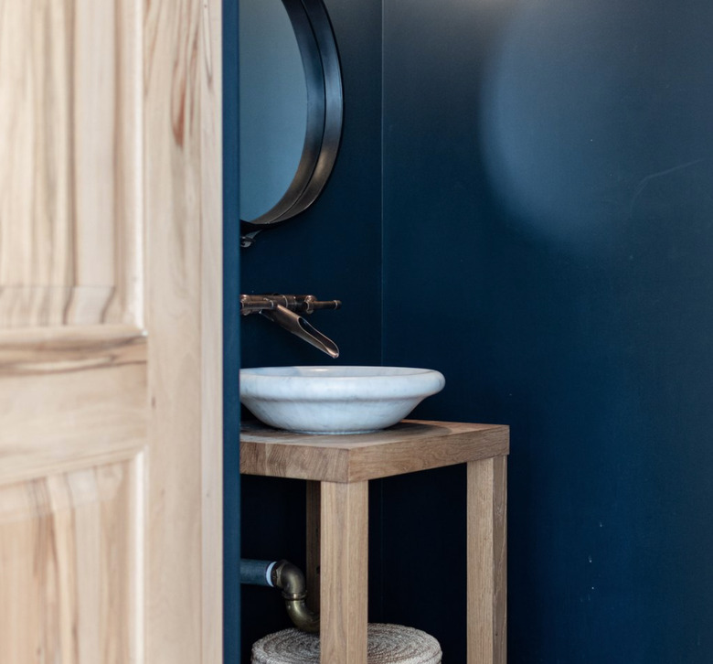 Navy bathroom with white bowl sink, brass Wall-Mounted Bathroom Faucet, round bowl sink.