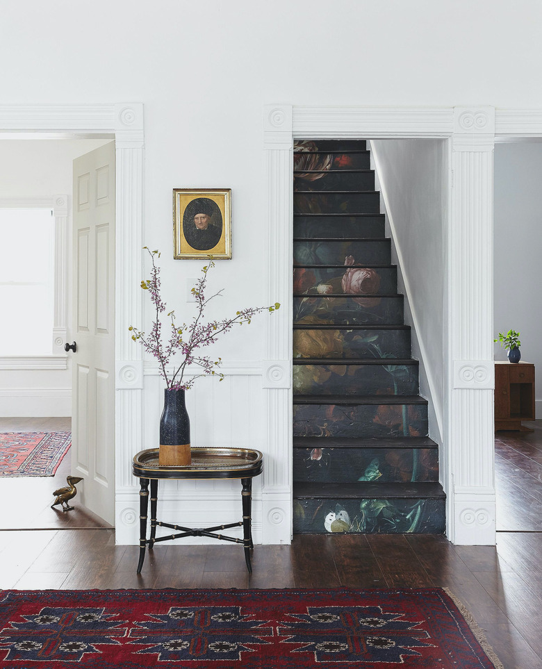 white entry with moody stairs wallpaper on risers with wood treads