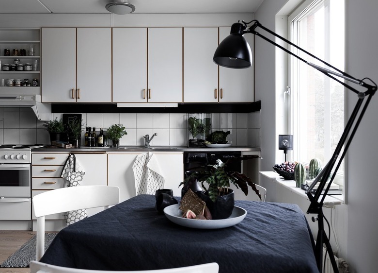 white kitchen with moody lighting and stainless steel countertops