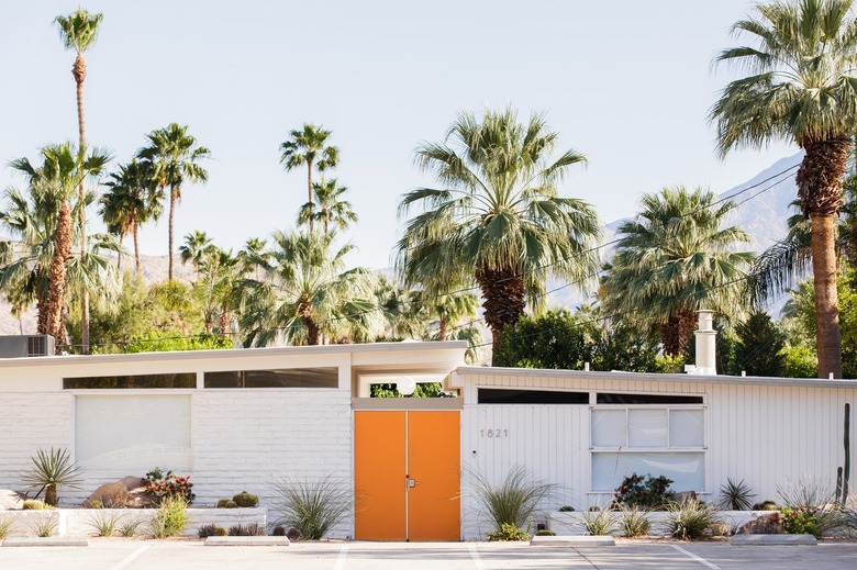 a white house with an orange door, a nearly flat roof, and clerestory windows