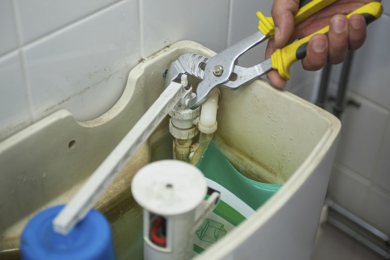 Close up of hand repairing toilet