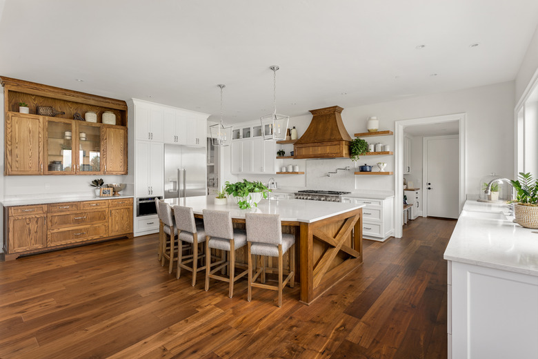 beautiful kitchen in new luxury home with island, pendant lights, and hardwood floors.