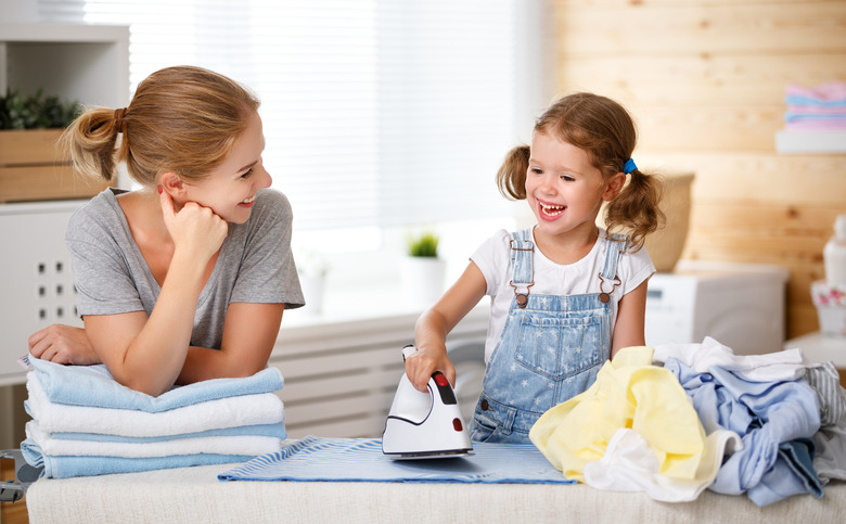 Happy family mother housewife and child daughter ironing clothes   in laundry