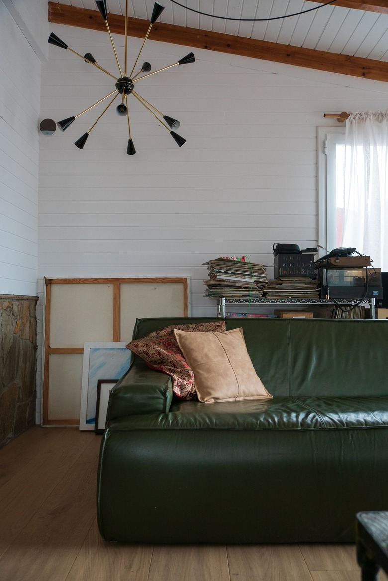 Eclectic living room with a green couch, modern chandelier and wood beam ceiling