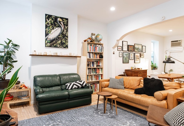 Living room with green leather loveseat and fawn leather couch with two round nesting tables