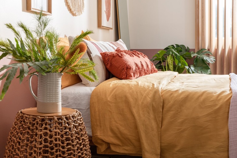 Bedroom with beige walls, and yellow and orange bedding