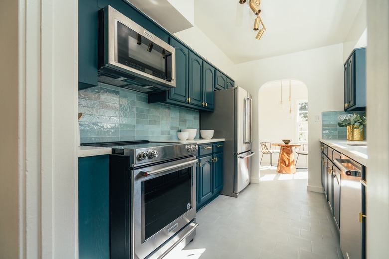 Kitchen with blue cabinets and blue tile, and brass ceiling lighting fixture.